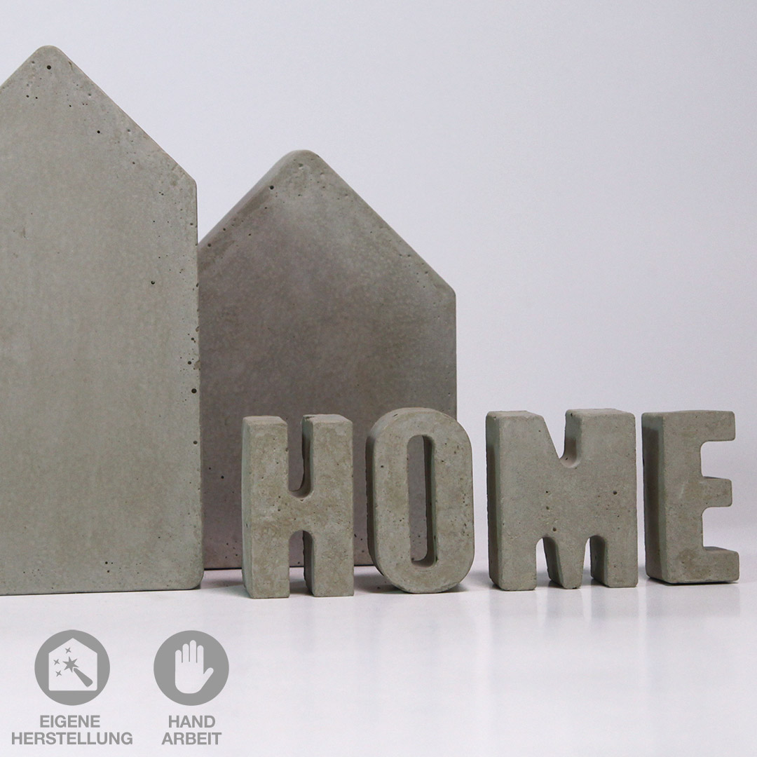 Hellgraue, handgefertigte Beton-Häuser mit dem Schriftzug "HOME" aus Beton.