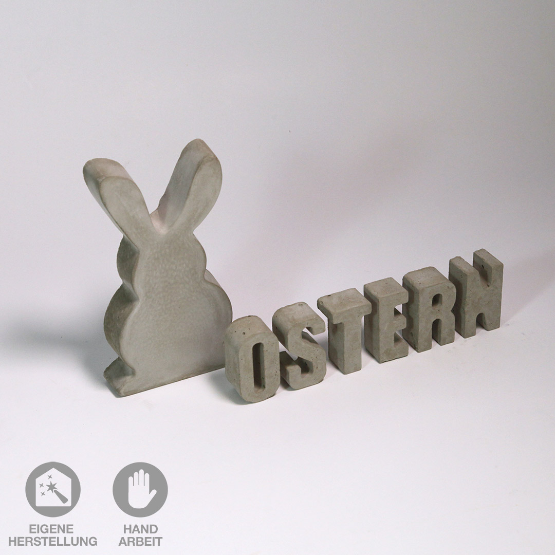 Dekorativer, grauer Beton-Hase und dazu passender Schriftzug "OSTERN".