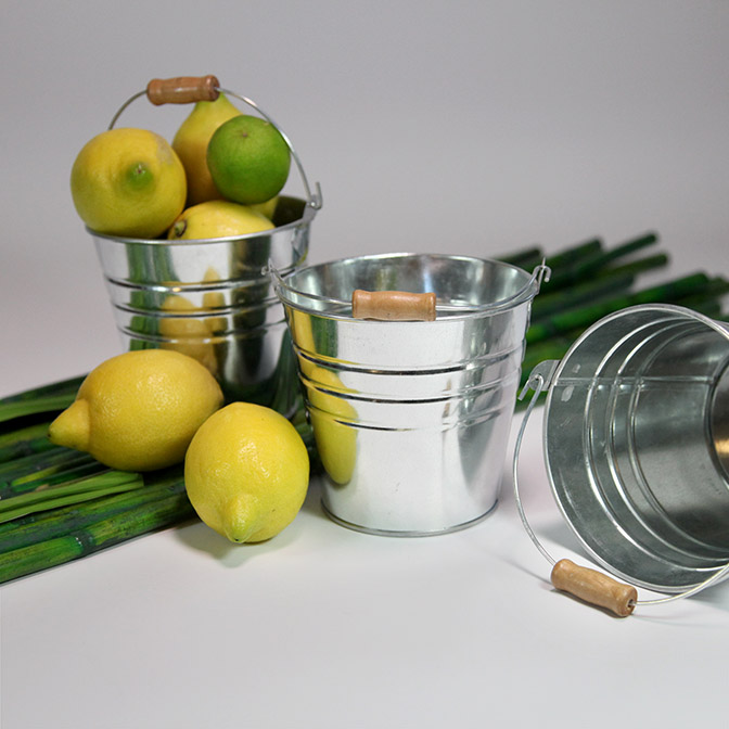 Deko-Eimer aus Metall mit Holzgriff. Hier mir grünen Bambus-Stangen und Zitronen dekoriert