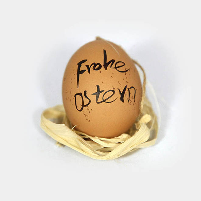 Braunes Hühner-Ei bemalt mit "Frohe Ostern"