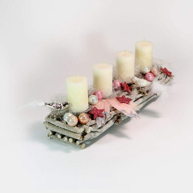 Längliches Advents-Gesteck aus Wurzeln mit rosafarbenen Vögeln, Herzen, Sternen und Zapfen. Dazu Engelshaar, rosa-silberne Engels-Flügel und weiße Kerzen.