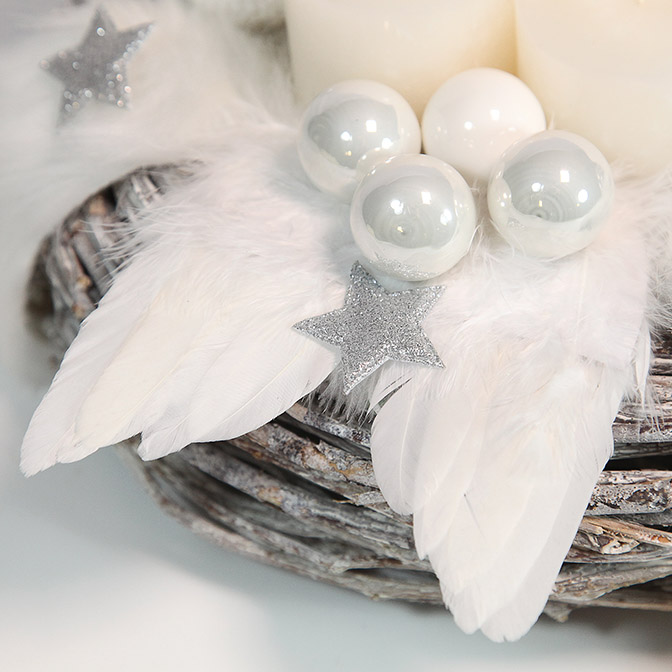 Weiße Engelsflügel, weißen Glas-Kugeln und silbernen Sternen auf Adventskranz aus hellem Reben-Holz mit weißer Dekoration.