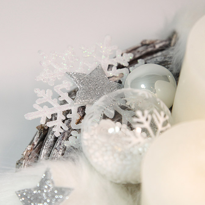 Ausschnitt aus einem pompösen, weißen Adventskranz aus Holz mit weißen Engelsflügeln, weißen Glas-Kugeln, Glas-Kugeln mit Kunst-Schnee befüllt und mit Schneekristallen bemalt, weißen Kerzen, silbernen Sternen, glimmernden Schneekristallen und Kunstfell-Band.