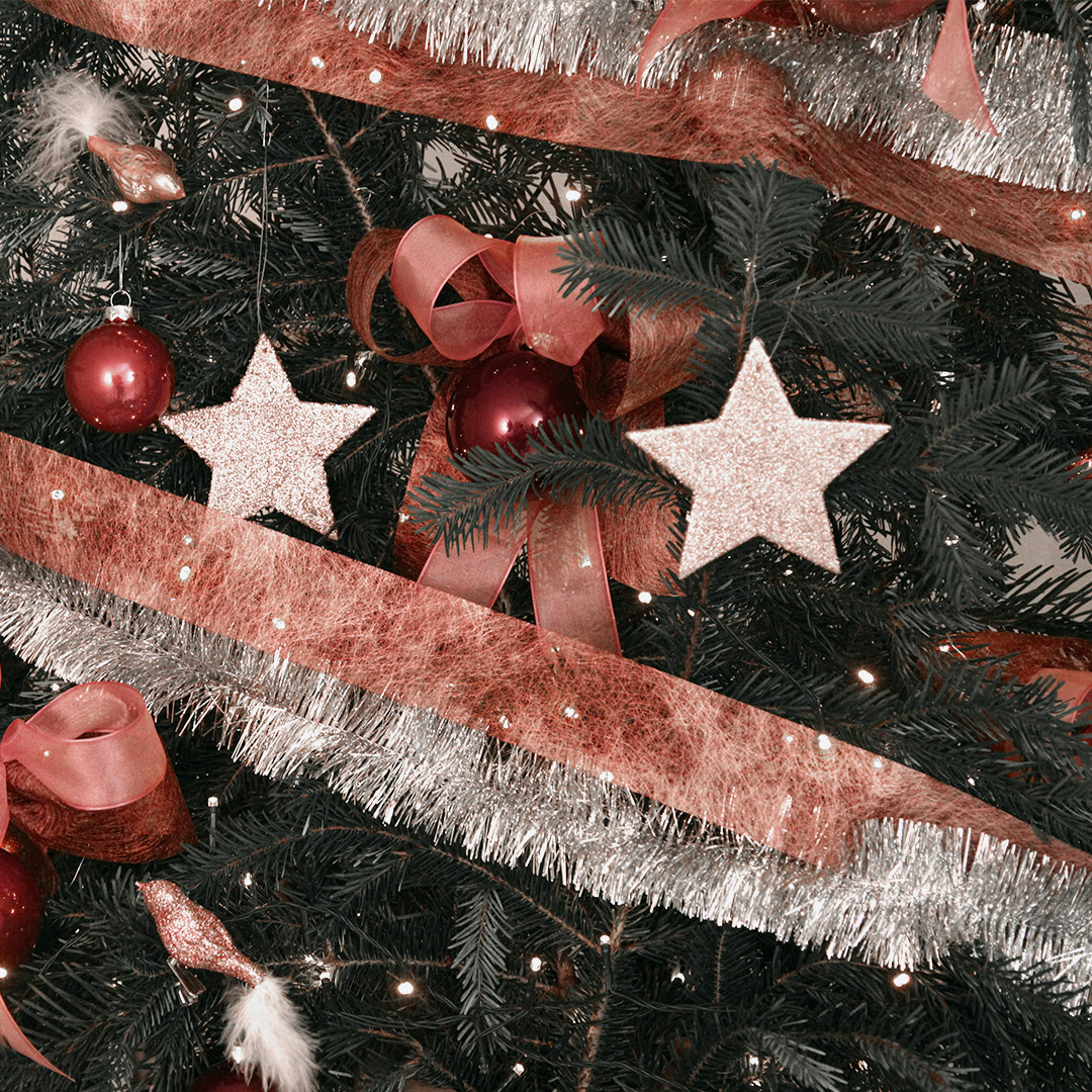 Nahaufnahme des Weihnachtsbaum-Deko-Sets "berry chic" mit üppigen, großen Doppelschleifen, Weihnachtsbaumkugeln aus Glas, Glasvögel mit Federschwanz, beglitterte Sterne, einem breiten altrosafarbenes Band und einer Limetta-Girlande. Das Ganze ist in einem gedeckten, harmonischen Beerenton gehalten.