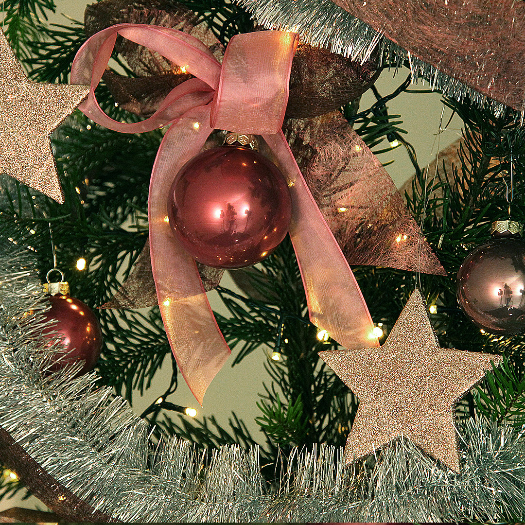 Ausschnitt des glamourösen Weihnachtsbaum-Deko-Sets "berry chic" mit üppigen, großen Doppel-Schleifen, Weihnachtsbaumkugeln aus Glas und beglitterten Sternen.