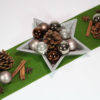 Silberne Stern-Schale aus Holz mit Zapfen, Zimtstangen, Stern-Anis und kleinen Weihnachts-Kugeln.