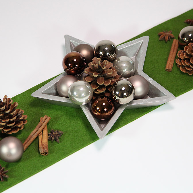 Silberne Stern-Schale aus Holz mit Zapfen, Zimtstangen, Stern-Anis und kleinen Weihnachts-Kugeln.