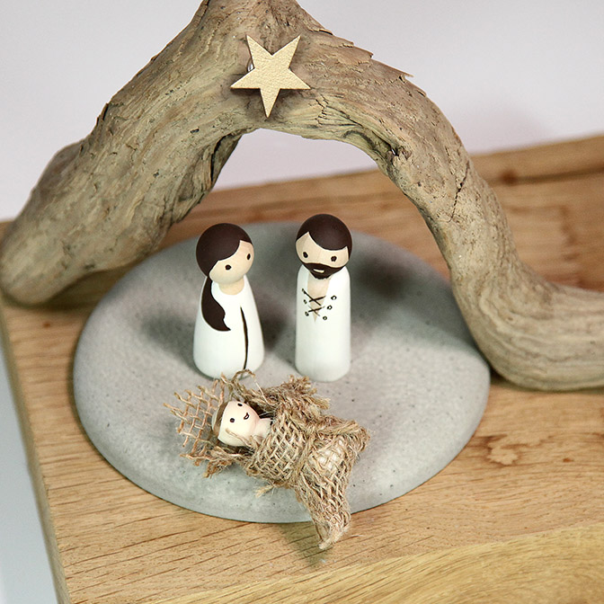 Von Hand bemalte Krippenfiguren mit Maria und Josef und Jesuskind auf einer Beton-Platte mit Stall.