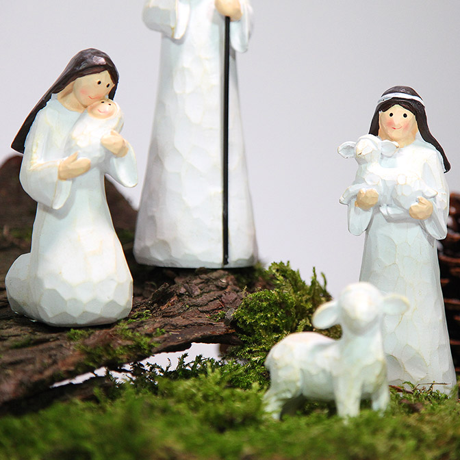 Ausschnitt von handgemachten Krippenfiguren (Maria, Josef und Jesuskind, Hirte mit Schafen und Esel) auf einem Stück Rinde. Kombiniert mit Zapfen und Moos.