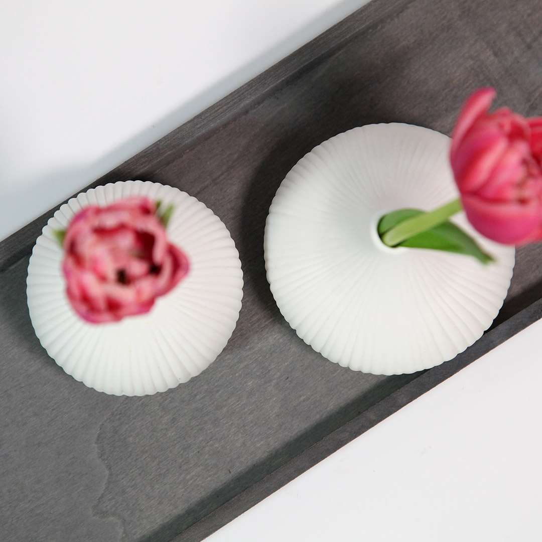 Vogelperspektive der Tischdekoration im Scandi-Style. Weiße Vasen mit Tulpen auf einem grauen Tablett.