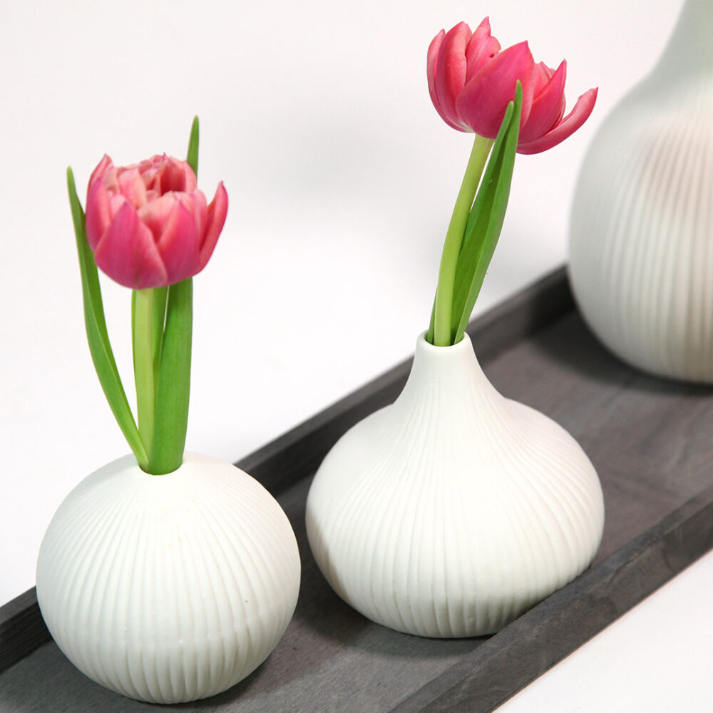 Frühlings-Deko im Scandi-Style. Weiße gerillte Vasen mit Tulpen auf einem grauen Holz-Tablett.