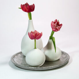 Ein Scandi-Style Deko-Beispiel sind diese drei weißen Kermaik-Vasen auf einem silbernen Teller im Used-Look.