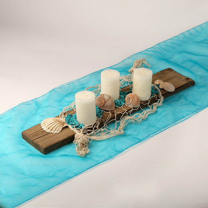 Dekoratives Holzbrett mit Kerzen, Muscheln, Deko-Steinen und Netz. Alles in türkis, wollweiß und beige gehalten.