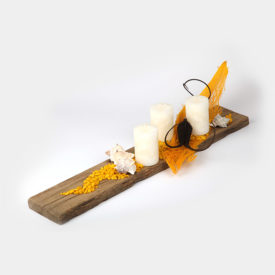 Ein dekoratives Holz-Brett bestückt mit wollweißen Kerzen, dekorativen, goldgelben Deko-Steinen und einem länglichen, sonnengelben Stück Palmfaser. Das Ganze wird abgerundet durch zwei dunkelbraune Naturschoten und wunderschöne Zacken-Muscheln in creme.