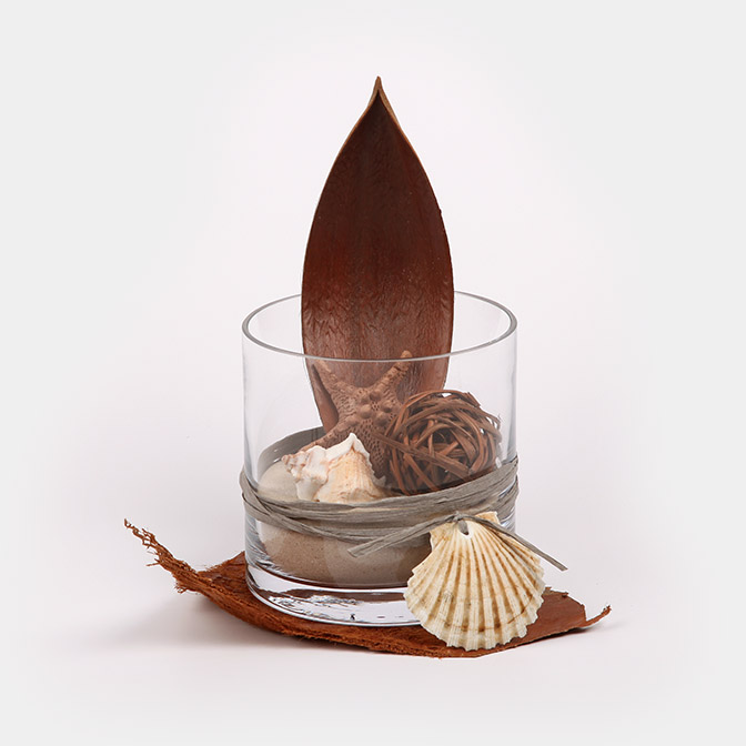 Unser Deko-Vase "Afrika-Safari" besteht aus einem Glas-Zylinder befüllt mit feinstem Quarzsand, welcher sich mit einem Cocos-Schale-Palmenblatt, einem getöpferten Seestern, Muscheln und einer gebundenen Deko-Kugel aus Ästen schmückt.