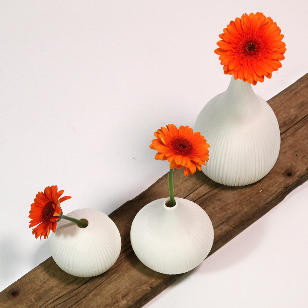 Weißes Deko-Set "Scandi-Vasen auf Barnwood" dekoriert mit orangen Gerberas.