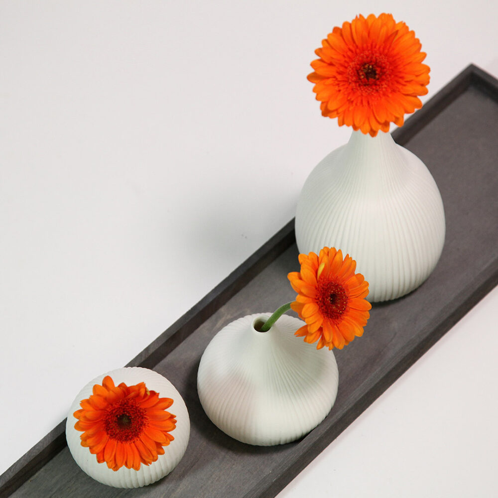 Dekobeispiel: Drei orangene Gerberas in unserem Scandi-Deko-Set, bestehend aus 3 weißen Vasen und einem Holz-Tablett.